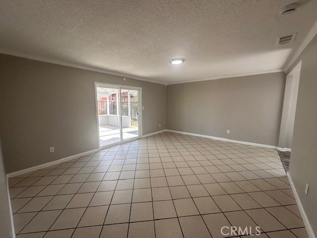 410 Orange Ave, Los Banos, CA 93635 - empty room featuring a textured ceiling, ornamental molding, and light tile patterned floors