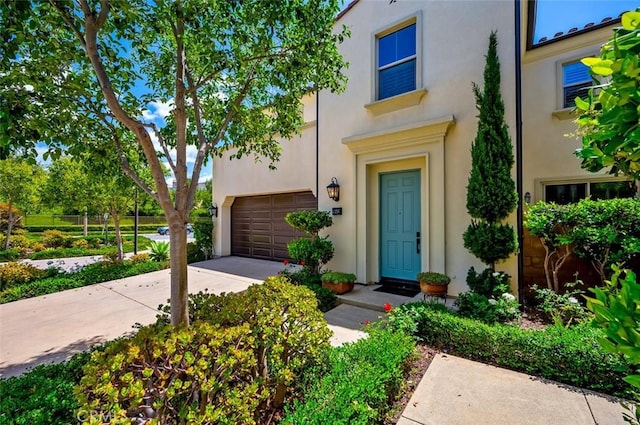 126 Brambles, Irvine, CA 92618 - view of property featuring a garage, stucco siding, and driveway