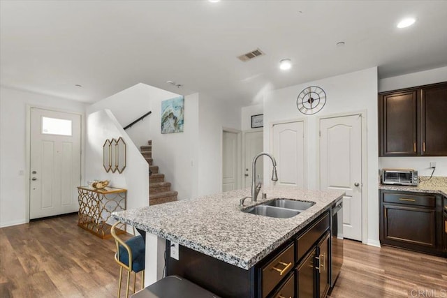 861 Colton Ave, Colton, CA 92324 - kitchen featuring a sink, dishwashing machine, dark wood-style flooring, light stone countertops, and an island with sink