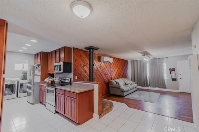 5805 Vista Del Cerro, Oroville, CA 95966 - kitchen with stainless steel appliances, washer and clothes dryer, a wood stove, a textured ceiling, and wood walls