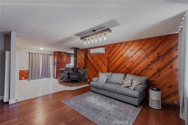 5805 Vista Del Cerro, Oroville, CA 95966 - living room with a wall unit AC, wooden walls, a wood stove, light wood-style flooring, and a textured ceiling