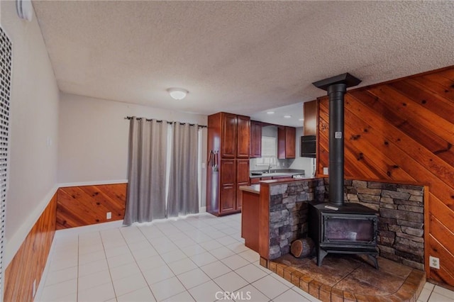 5805 Vista Del Cerro, Oroville, CA 95966 - kitchen featuring wooden walls, a textured ceiling, a peninsula, a wood stove, and light tile patterned floors