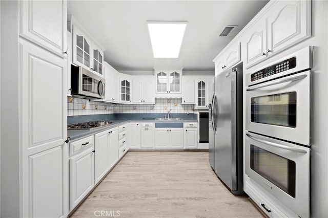 10441 La Mirada Blvd, Whittier, CA 90604 - kitchen with stainless steel appliances, dark countertops, light wood-style floors, and white cabinets