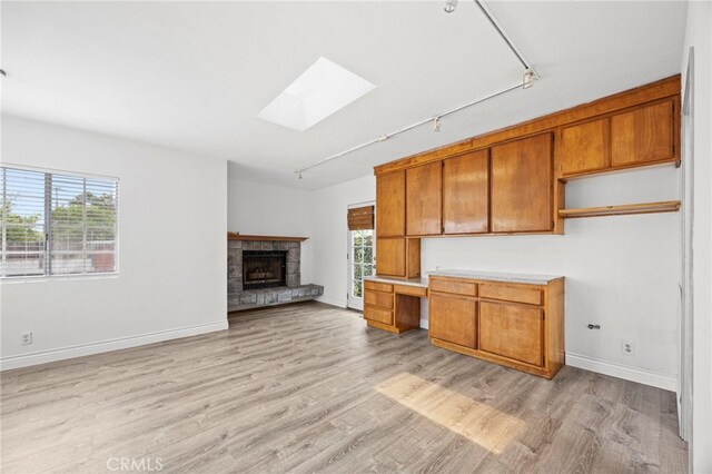 10441 La Mirada Blvd, Whittier, CA 90604 - kitchen featuring rail lighting, a skylight, brown cabinets, light wood-style flooring, and baseboards