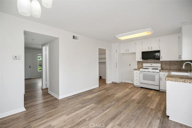 101 Briarwood Unit 3, Irvine, CA 92604 - kitchen featuring white range with gas stovetop, black microwave, light wood-style floors, and backsplash