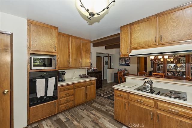 1249 Yellowstone Dr, Lake Arrowhead, CA 92352 - kitchen with black appliances, dark wood-style flooring, light countertops, under cabinet range hood, and brown cabinetry