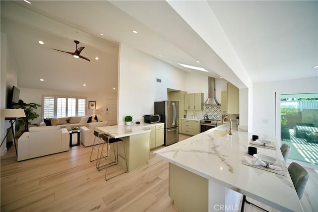 21651 Hilaria, Huntington Beach, CA 92646 - kitchen featuring wall chimney range hood, appliances with stainless steel finishes, a peninsula, a kitchen breakfast bar, and plenty of natural light