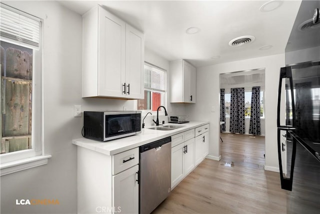 3113 Occidental St, Bakersfield, CA 93305 - kitchen with stainless steel dishwasher, a sink, white cabinets, light countertops, and light wood-style flooring