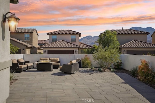 80218 Whisper Rock Way, La Quinta, CA 92253 - patio terrace at dusk featuring an outdoor living space with a fire pit, a fenced backyard, and a mountain view