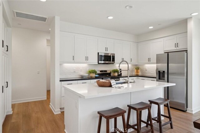 80218 Whisper Rock Way, La Quinta, CA 92253 - kitchen featuring appliances with stainless steel finishes, a sink, a breakfast bar area, light wood-style floors, and recessed lighting