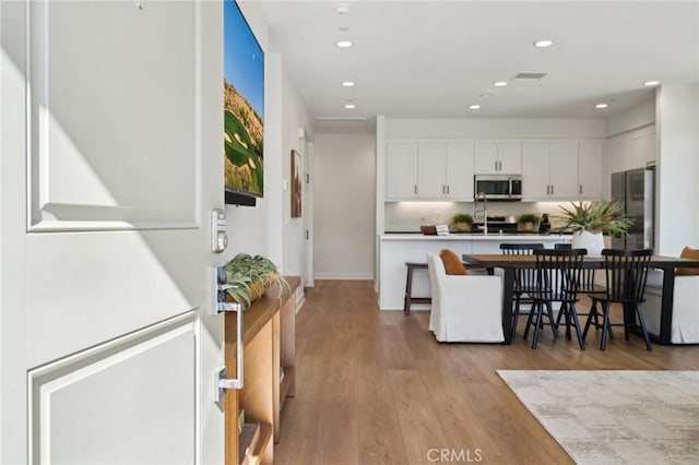 80218 Whisper Rock Way, La Quinta, CA 92253 - kitchen with appliances with stainless steel finishes, white cabinetry, a breakfast bar area, light wood-style floors, and recessed lighting