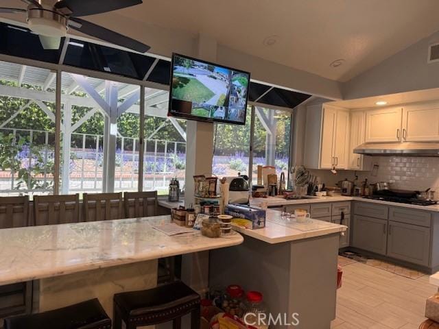 kitchen featuring under cabinet range hood, black gas cooktop, light countertops, ceiling fan, and a sink