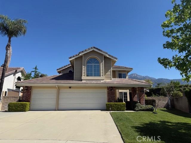 traditional-style house with concrete driveway, brick siding, a tile roof, and a mountain view