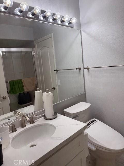 full bath with a stall shower, toilet, and vanity