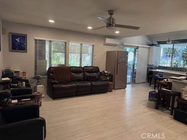 living room with a wall mounted AC, a ceiling fan, recessed lighting, and light wood-type flooring
