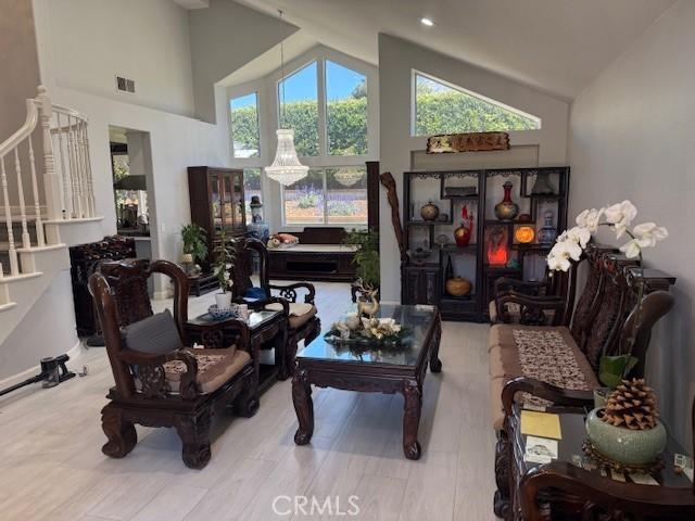 living room featuring high vaulted ceiling, healthy amount of natural light, stairs, and wood finished floors