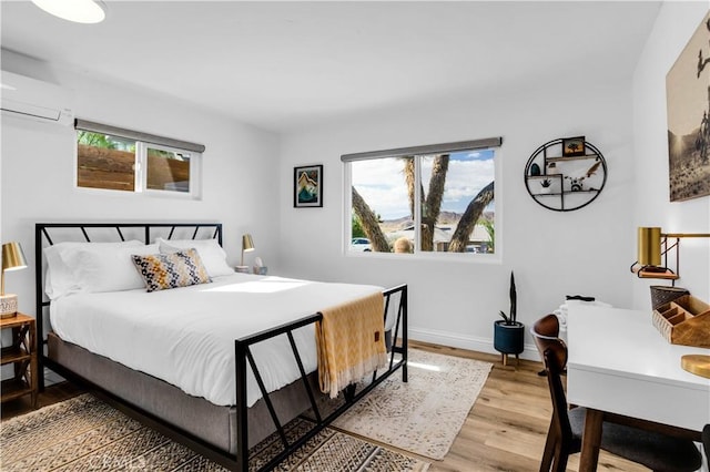 61475 Alta Vista Dr, Joshua Tree, CA 92252 - bedroom featuring a wall unit AC, light wood-style flooring, and baseboards
