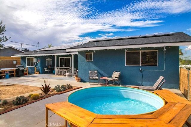 61475 Alta Vista Dr, Joshua Tree, CA 92252 - rear view of house featuring stucco siding, solar panels, a patio area, fence, and a jacuzzi