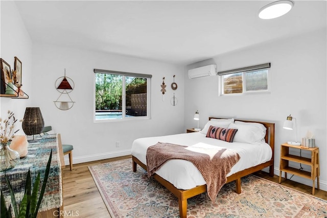 61475 Alta Vista Dr, Joshua Tree, CA 92252 - bedroom featuring a wall mounted AC, baseboards, and light wood finished floors