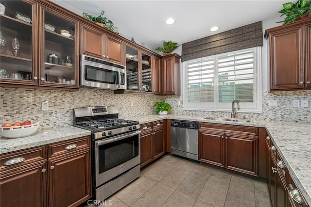 3105 E Discovery St, Ontario, CA 91762 - kitchen featuring appliances with stainless steel finishes, a sink, decorative backsplash, light tile patterned flooring, and light stone countertops
