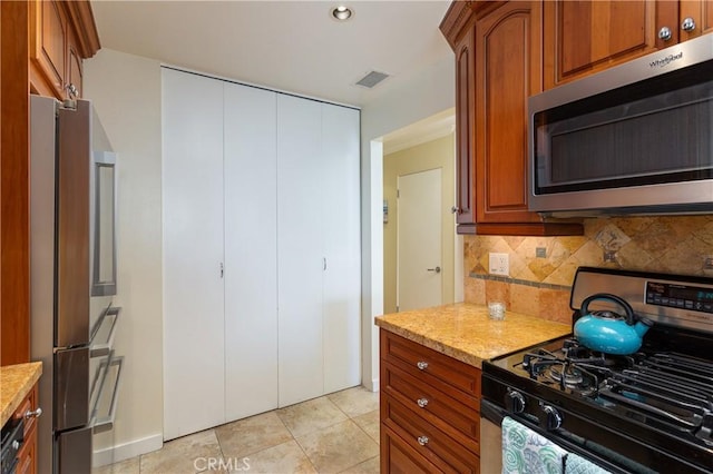 379 Camino, San Clemente, San Clemente, CA 92672 - kitchen with stainless steel appliances, decorative backsplash, light stone counters, brown cabinetry, and light tile patterned floors