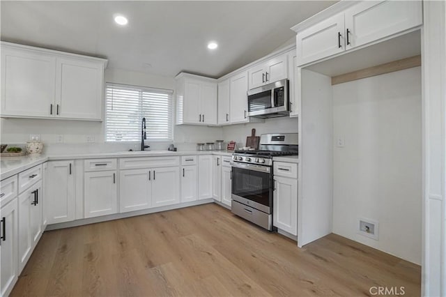 6294 Sunnyslope Rd, Phelan, CA 92371 - kitchen with appliances with stainless steel finishes, a sink, white cabinets, light wood-style flooring, and recessed lighting