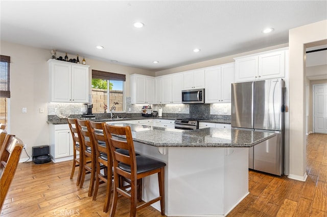 27335 Wedgewood Way, Murrieta, CA 92562 - kitchen featuring stainless steel appliances, light wood-style flooring, a center island, tasteful backsplash, and white cabinets