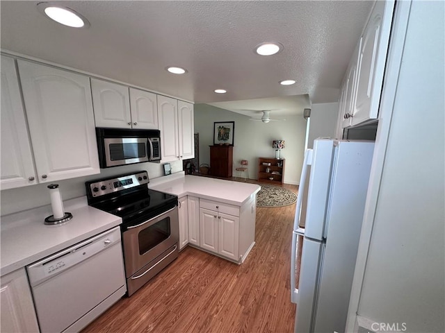 253 Calle Aragon Unit F, Laguna Woods, CA 92637 - kitchen featuring stainless steel appliances, a peninsula, white cabinets, a ceiling fan, and light wood finished floors