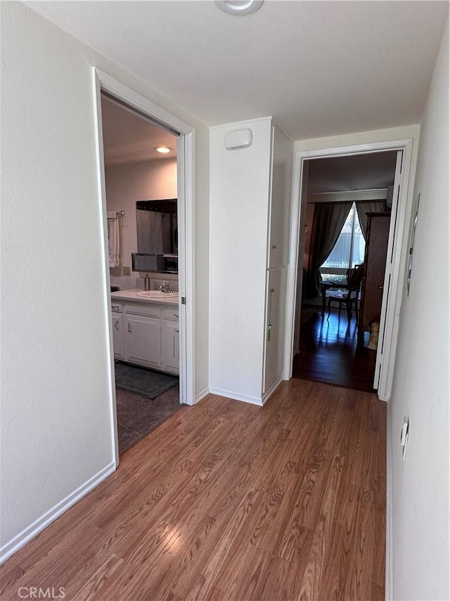 253 Calle Aragon Unit F, Laguna Woods, CA 92637 - hallway with a sink, wood finished floors, and baseboards