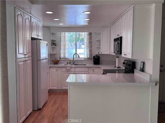 253 Calle Aragon Unit F, Laguna Woods, CA 92637 - kitchen with black appliances, a sink, open shelves, a peninsula, and light wood-style floors