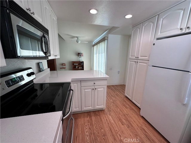 253 Calle Aragon Unit F, Laguna Woods, CA 92637 - kitchen with stainless steel appliances, light wood-style floors, white cabinetry, a peninsula, and light countertops