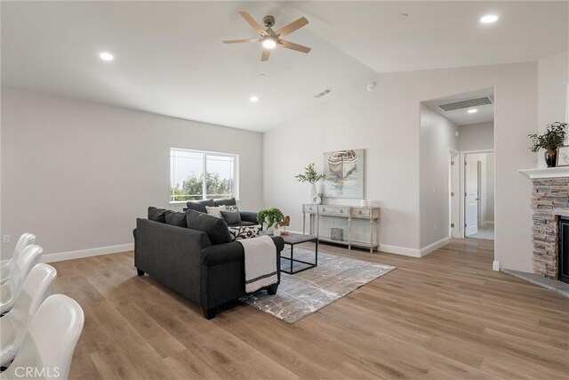 5122 Feather Rock Ct, Paradise, CA 95969 - living room featuring a ceiling fan, vaulted ceiling, light wood-style floors, baseboards, and a stone fireplace