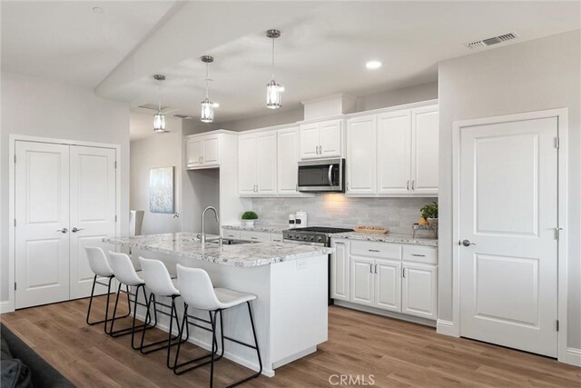 5122 Feather Rock Ct, Paradise, CA 95969 - kitchen featuring stainless steel appliances, white cabinets, decorative backsplash, a kitchen breakfast bar, and recessed lighting