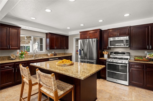 4571 Mimosa Dr, Yorba Linda, CA 92886 - kitchen with appliances with stainless steel finishes, a sink, a center island, a kitchen breakfast bar, and light stone countertops