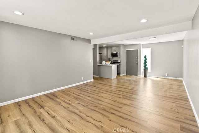 unfurnished living room with recessed lighting, baseboards, and light wood-style flooring