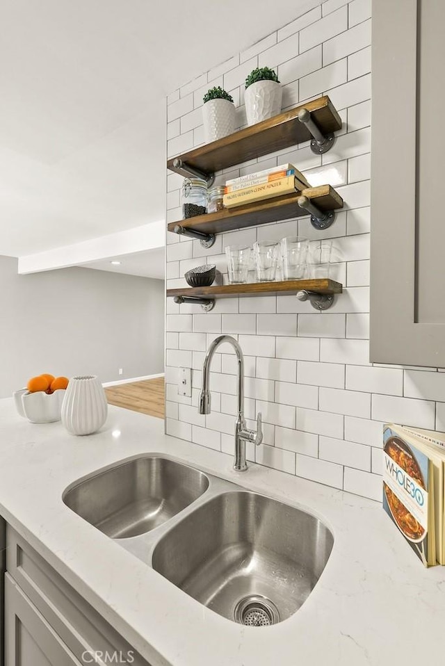 18620 Hatteras St Unit 223, Tarzana, CA 91356 - kitchen with a sink, decorative backsplash, open shelves, and light stone counters