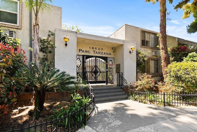 property entrance with fence and stucco siding