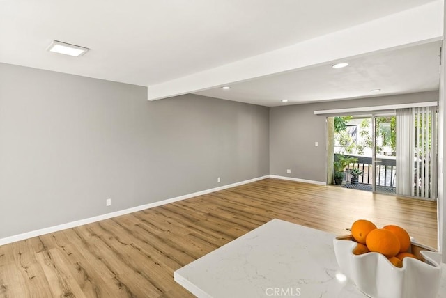 unfurnished living room with wood finished floors, baseboards, and recessed lighting
