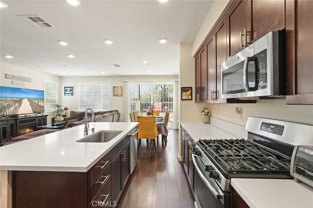 kitchen with stainless steel appliances, a sink, open floor plan, recessed lighting, and light countertops