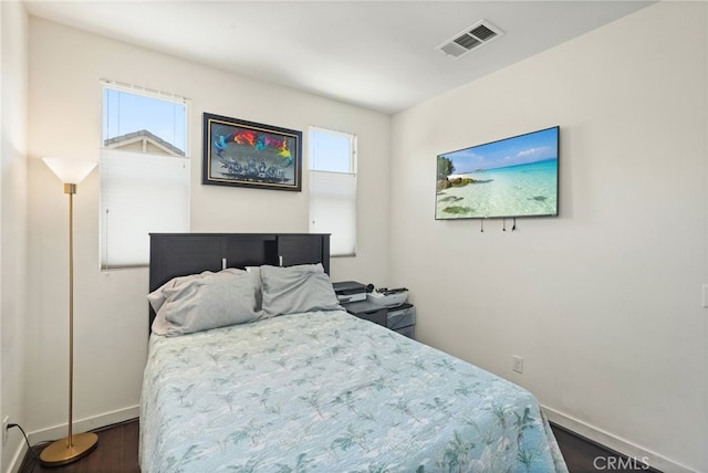 bedroom with multiple windows, dark wood finished floors, and baseboards