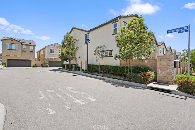 view of asphalt road with a residential view, street lighting, and curbs