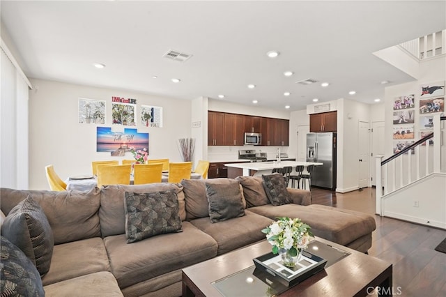 living area with dark wood-type flooring, recessed lighting, and stairs