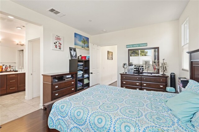 bedroom featuring wood finished floors, ensuite bathroom, and multiple windows