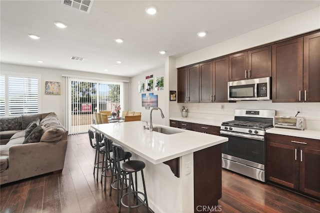 kitchen featuring stainless steel appliances, a sink, open floor plan, dark wood-type flooring, and recessed lighting