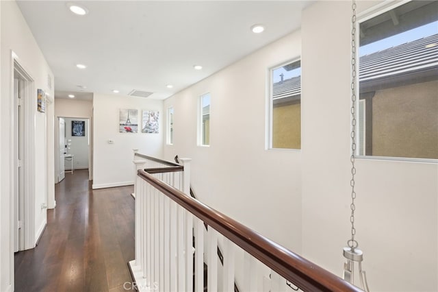 hallway with an upstairs landing, recessed lighting, dark wood-style flooring, and baseboards
