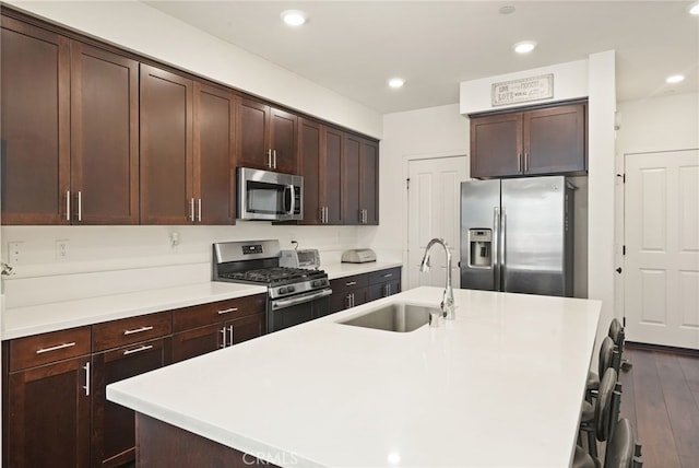 kitchen featuring appliances with stainless steel finishes, a sink, an island with sink, light countertops, and recessed lighting