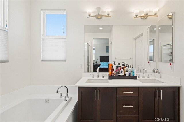 ensuite bathroom featuring a garden tub, double vanity, and recessed lighting