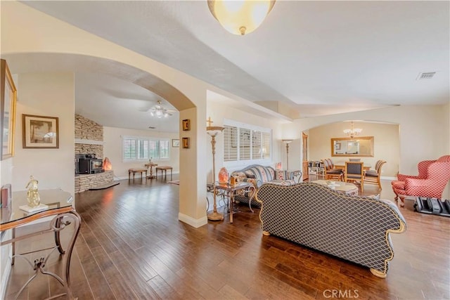 4428 Trumbo Ct, Phelan, CA 92371 - living area featuring arched walkways, wood finished floors, ceiling fan, a stone fireplace, and a chandelier
