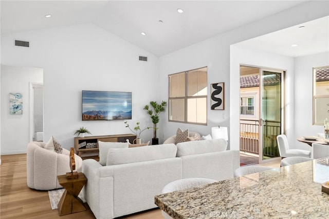 living area with light wood-style flooring, recessed lighting, and high vaulted ceiling