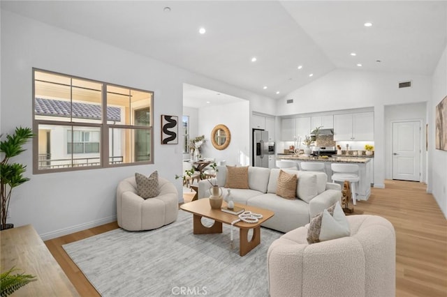 living area with light wood-style floors, recessed lighting, and high vaulted ceiling